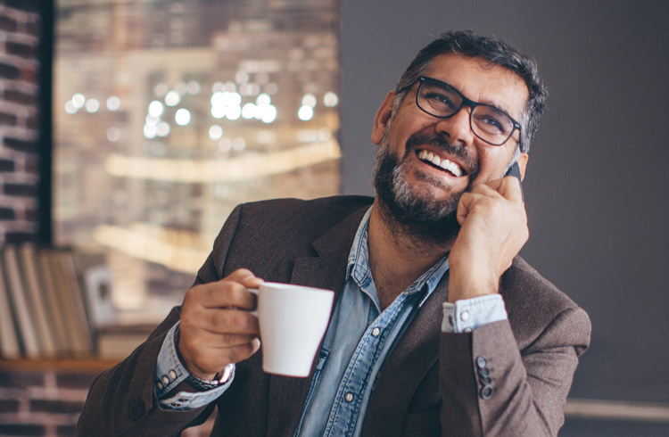 A middle aged man smiling while talking on the phone in a cafe